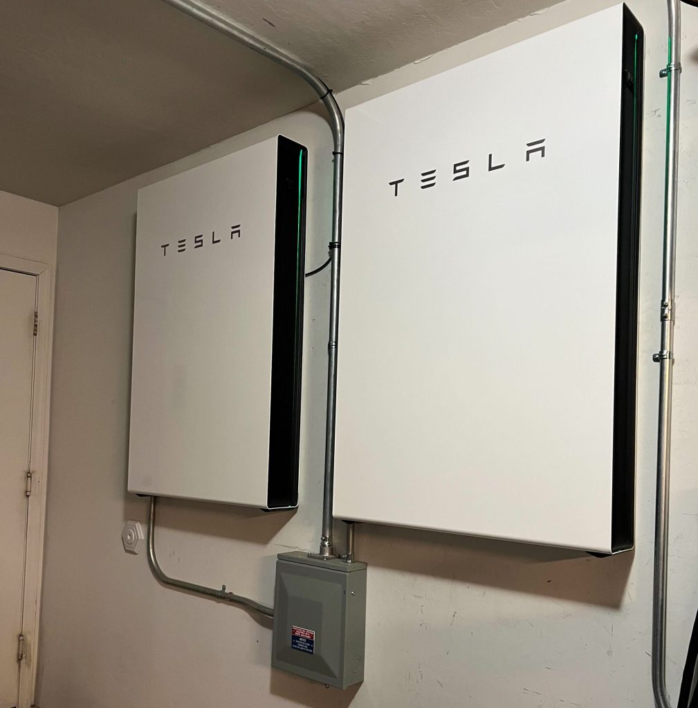 A home battery storage unit mounted on a wall beside rooftop solar equipment